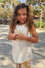 Girl wearing the Yellow Sun Cotton Set featuring a white sequined sun vest and yellow soleil motif printed trousers.