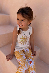 Girl wearing a yellow sun cotton set with a sequin soleil sun vest and matching printed trousers