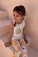 Girl wearing a yellow sun cotton set with a sequin soleil sun vest and matching printed trousers