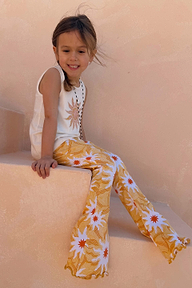 Girl sitting on stone stairs wearing a Yellow Sun Cotton Set with a sleeveless soleil vest and flared trousers.