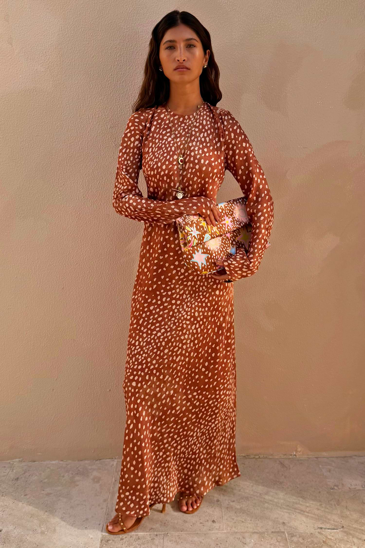 Model wearing the Fawn Soho Dress, a brown satin-like maxi with a cream deer print and long flared sleeves.