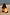 Thumbnail for Girl wearing the yellow sun print swimsuit with frill detailing while crouching on a sandy beach.