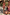 Thumbnail for Pink fruit print bikini set with a shirred bandeau top and ruffled bottoms worn by a girl at the beach.