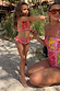 Pink fruit print bikini set with a shirred bandeau top and ruffled bottoms worn by a girl at the beach.