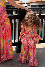 Child wearing the Girl's Pink Fruit Wide Leg Set featuring a peplum top and frilled flared trousers.