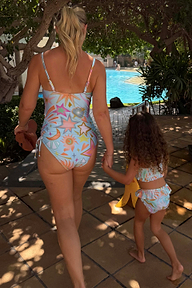 Girl's blue Starburst Crop Bikini Set with frill trims, walking towards a swimming pool on vacation.