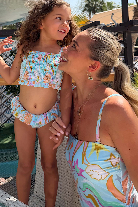 Girl wearing the blue Starburst Crop Bikini Set with smocked bandeau and frill details on a sunny vacation.