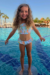 Blue Starburst Crop Bikini Set with smocked bandeau top and frill trims on a smiling girl in a sunny pool.