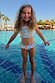 Blue Starburst Crop Bikini Set with smocked bandeau top and frill trims on a smiling girl in a sunny pool.