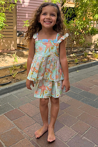 Girl wearing the blue Starburst Skirt Co-ord Set featuring a peplum top and tiered skirt with sun and star motifs.