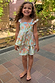 Girl wearing the blue Starburst Skirt Co-ord Set featuring a peplum top and tiered skirt with sun and star motifs.