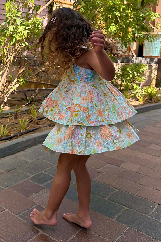 Girl wearing a blue cotton Starburst skirt co-ord set with pink sun and star motifs.