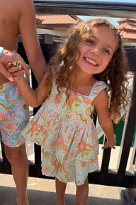 Smiling girl wearing the blue cotton Starburst Skirt Co-ord Set with a sun and star print.
