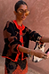 Model wearing the Tan Jaden Floral Jacquard cardigan with red trim, styled with gold jewellery and a beaded bag.