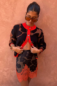 Model wearing Maeva Mini Skirt in Tan Jaden Floral Print with orange lace trim and matching knit cardigan.