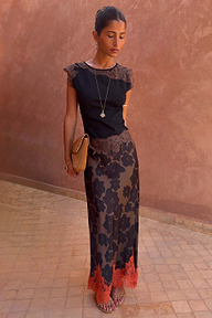 Modella con Gonna Maeva in stampa floreale Tan Jaden, orlo in pizzo arancione e top nero coordinato.
