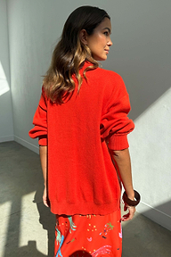 Cardigan Red Celestial in maglia rossa con maniche a sbuffo, visto dal retro con gonna a fantasia.