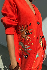 Cardigan Red Celestial rosso con ricami di sole e stelle e bottoni neri in primo piano.