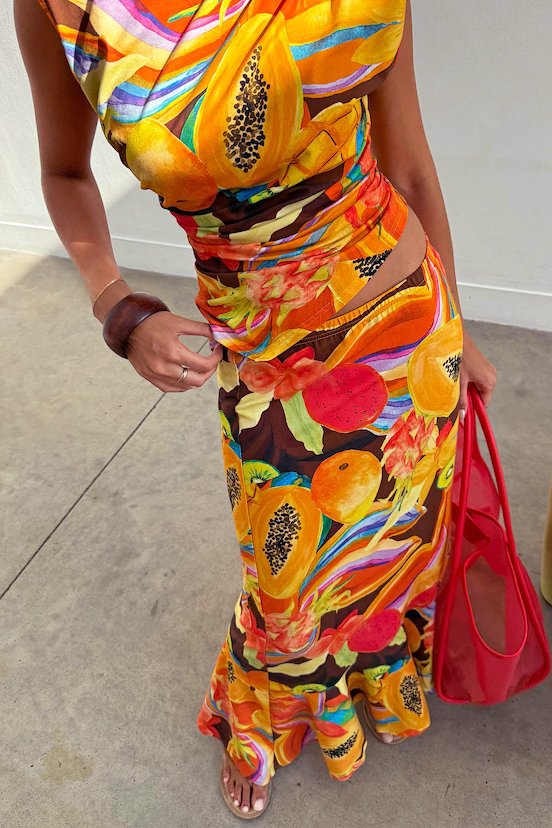 Rio A-Symmetric Skirt in a colourful tropical fruit print with angled panels, styled with a matching top.