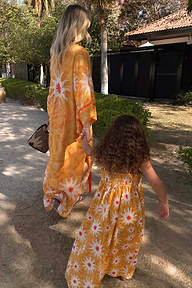 Girl's Yellow Cotton Sun Dress with a shirred top and sun print, worn by a child walking in a sunny setting.