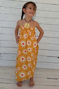 Young girl wearing a yellow cotton maxi sun dress with white sunburst prints and a shirred top.