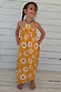 Young girl wearing a yellow cotton maxi sun dress with white sunburst prints and a shirred top.