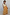 Thumbnail for Child model in a yellow sun print cotton maxi dress with a shirred waist against a white wooden wall.