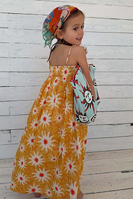Girl wearing a yellow cotton sun dress with white sun print and shirred top.