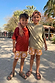 Boy's Yellow Sun Swim Shorts worn by two children on a sunny outdoor vacation with palm trees.