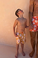 Boy wearing Yellow Sun Swim Shorts in a soleil print, holding hands with a man in matching swimwear.