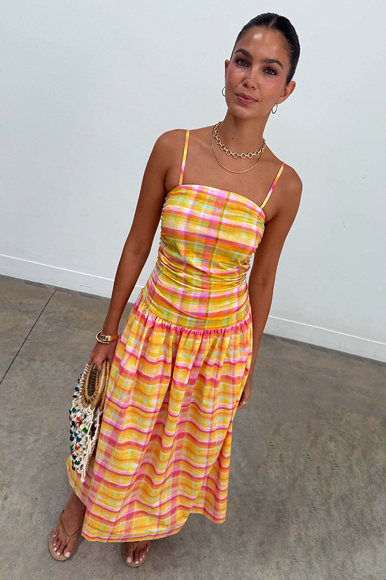 Model wearing the yellow, pink and orange Check Lola Mid-axi Dress with a ruched bodice.