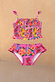 Girls pink Mediterranean fruit print bikini set featuring a shirred crop top and frilled bottoms.