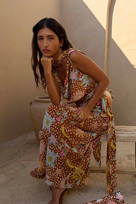 Abito midi Star Fawn Sophie marrone con stampa celestiale indossato da una modella seduta.
