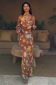 Modella indossa l'abito lungo Sophie Star Fawn marrone con stelle e pois e pochette coordinata.
