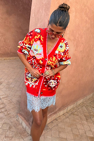 Modella con il cardigan rosso Martha Tomato Tapestry, motivi celesti e punto coperta a contrasto.