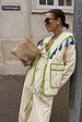 model is wearing the quilted striped jacket in a pastel yellow with the matching trouser and a suede bag 