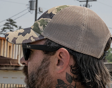 A man wearing a camo ripstop-style tactical hat.