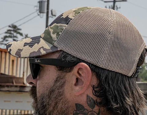 A man wearing a camo ripstop-style tactical hat.