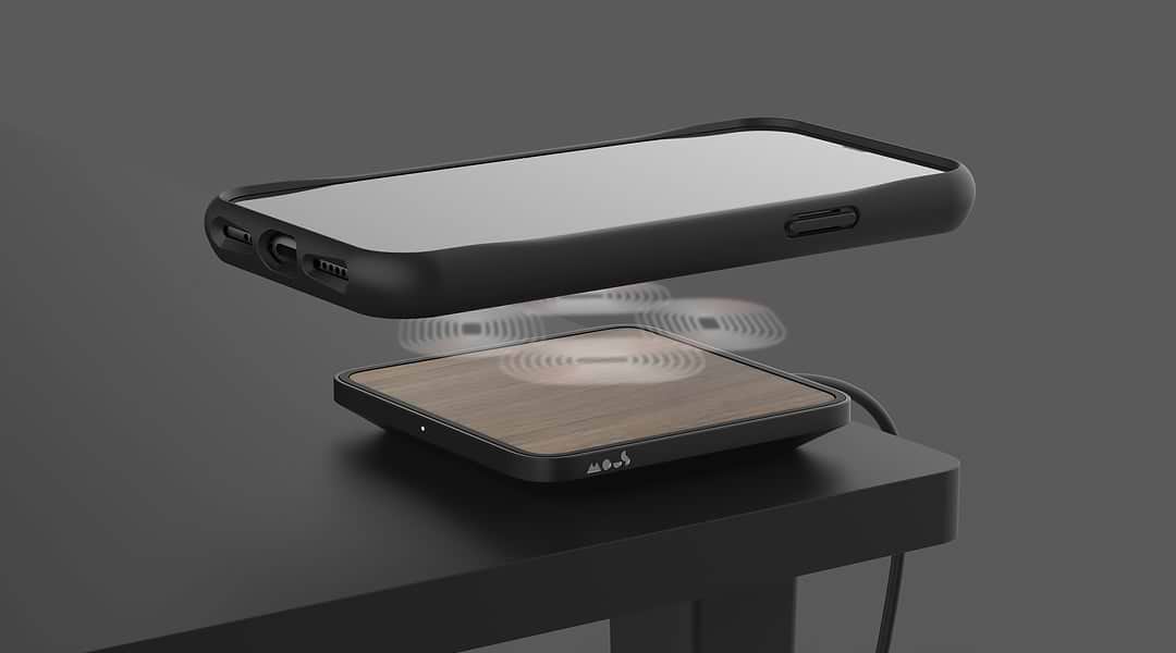 iPhone floating above a Mous wireless charger on a desk
