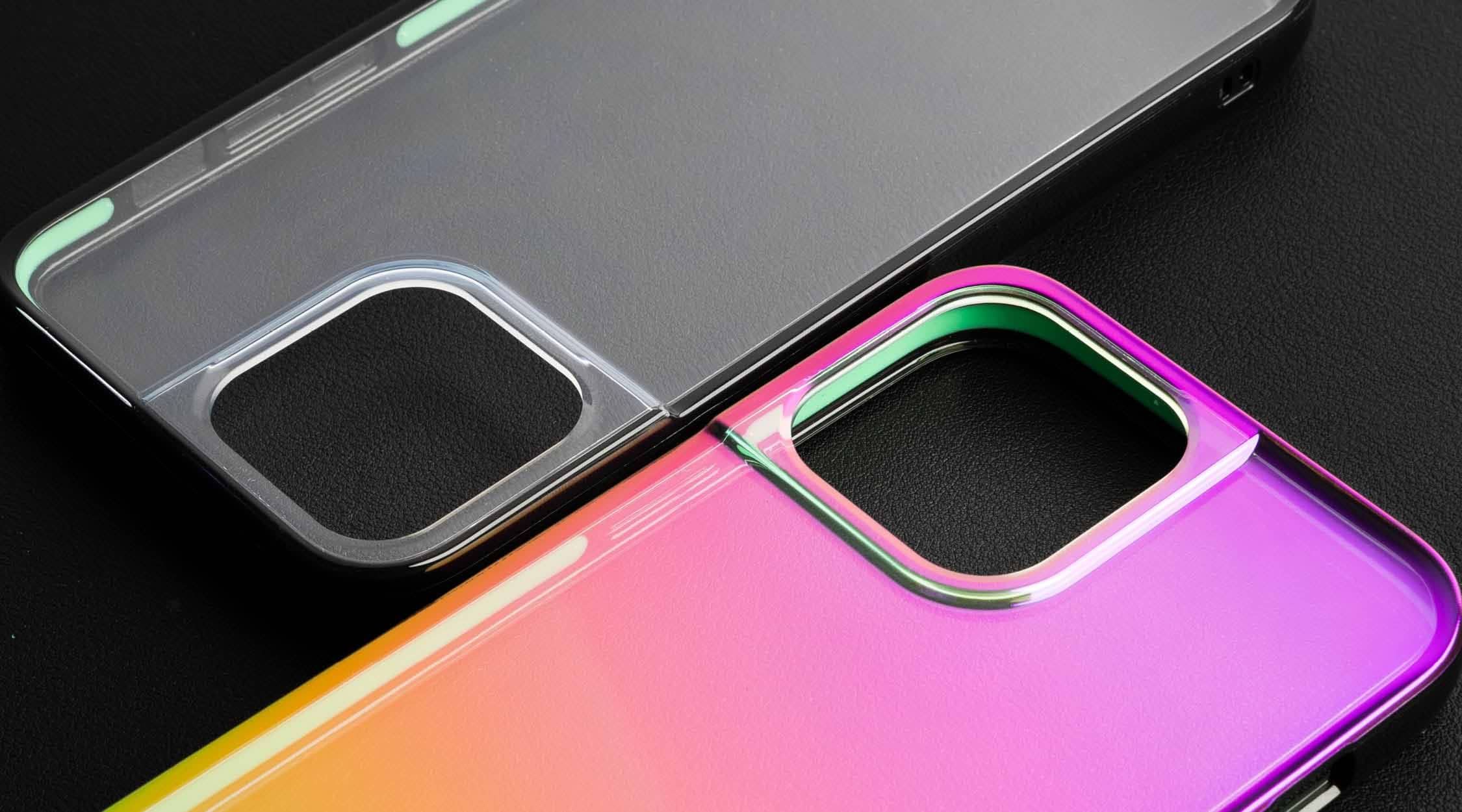Pink and yellow iridescent phone case for iPhone 13 Pro Max next to a clear iPhone case on a black leather background