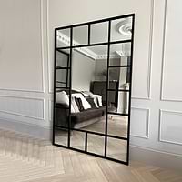 Black industrial full length metal window mirror leaning against wall