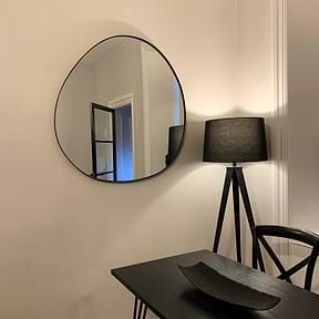 Black metal pond shaped irregular wall mirror displayed on wall