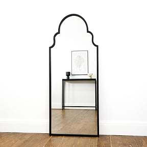 Black industrial arched metal extra large mirror leaning against wall