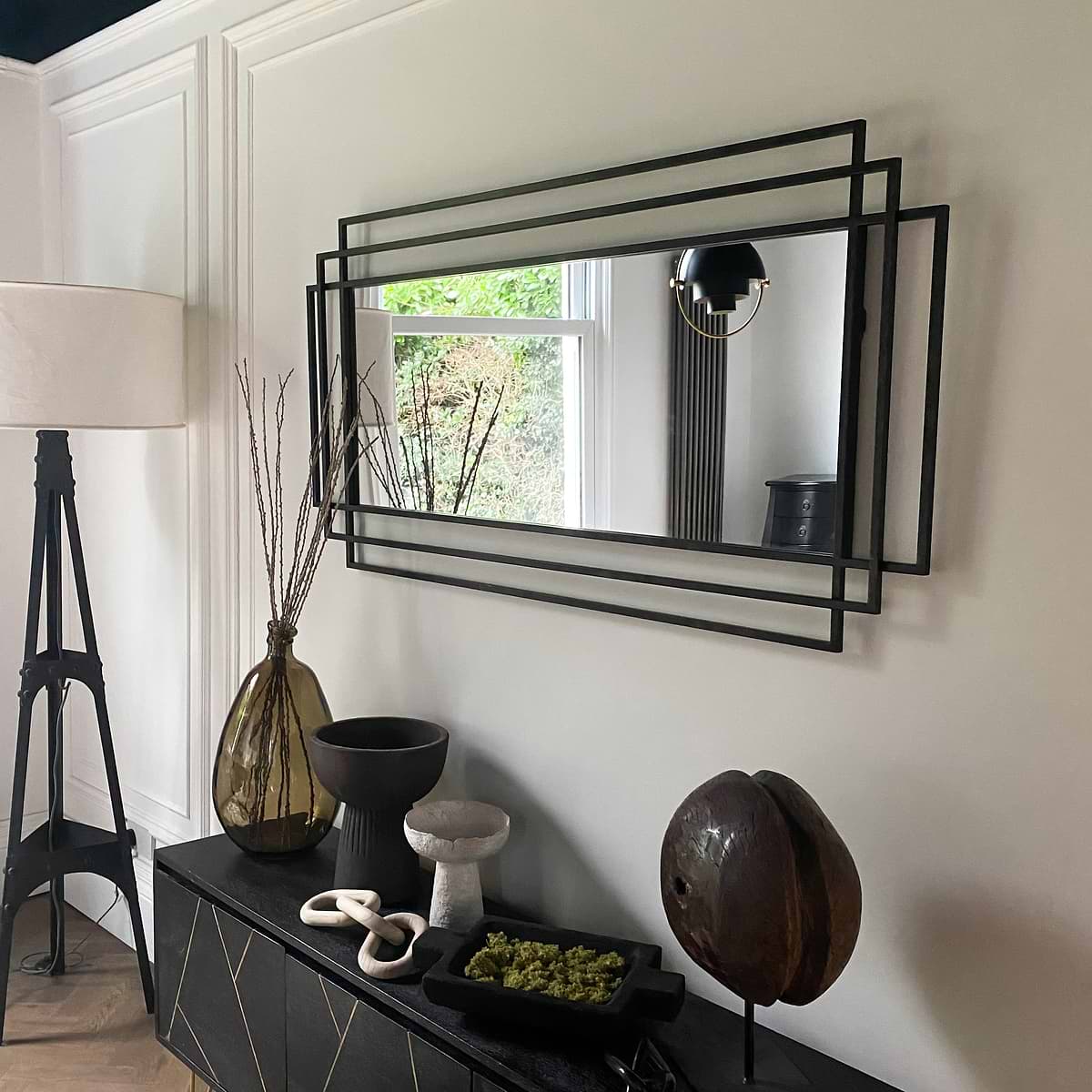 Large black rectangular metal mirror displayed on wall