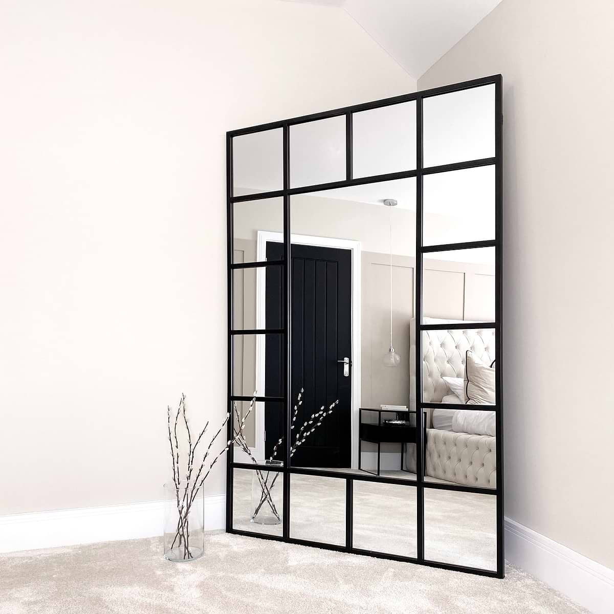 Black industrial full length metal window mirror in room corner