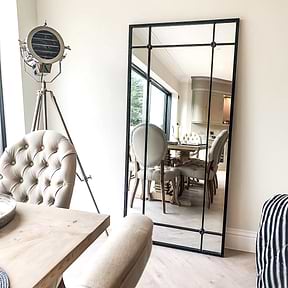 Black industrial full length metal mirror leaning against wall