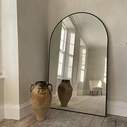 Black Full Length Arched Metal Mirror beside ceramic vase