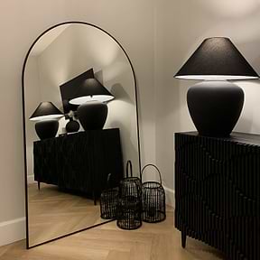 Black Full Length Arched Metal Mirror beside lamp
