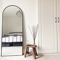 Black Full Length Arched Metal Mirror in bedroom beside bench