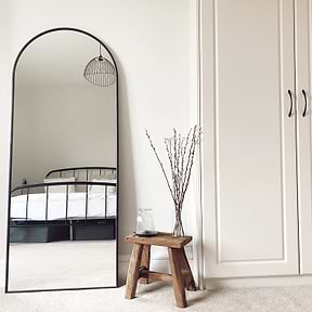Black Full Length Arched Metal Mirror in bedroom beside bench